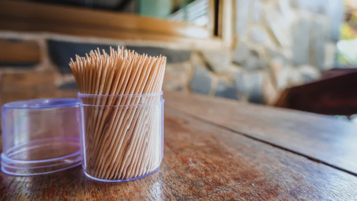 pile of toothpicks and a bottle of glue